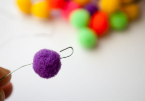 Hook end of floral wire to hold on mini pom poms when making mini pom pom Christmas ornaments