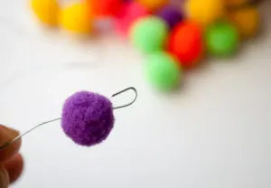 Hook end of floral wire to hold on mini pom poms when making mini pom pom Christmas ornaments