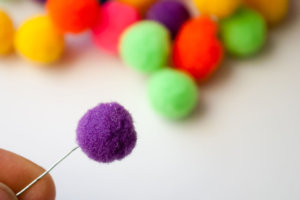 Pull hooked wire to the end of the pom pom to secure the pom pom