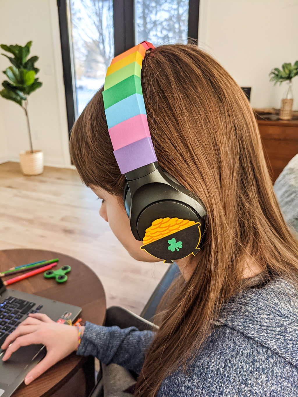 Kid wearing headphones decorated for St. Patrick's Day with rainbows and a pot of gold