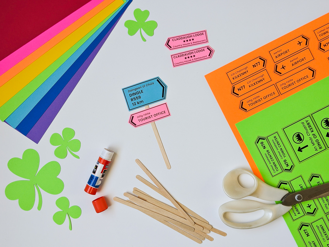 Making cupcake toppers for St. Patrick's Day using colorful paper and wooden coffee stir sticks