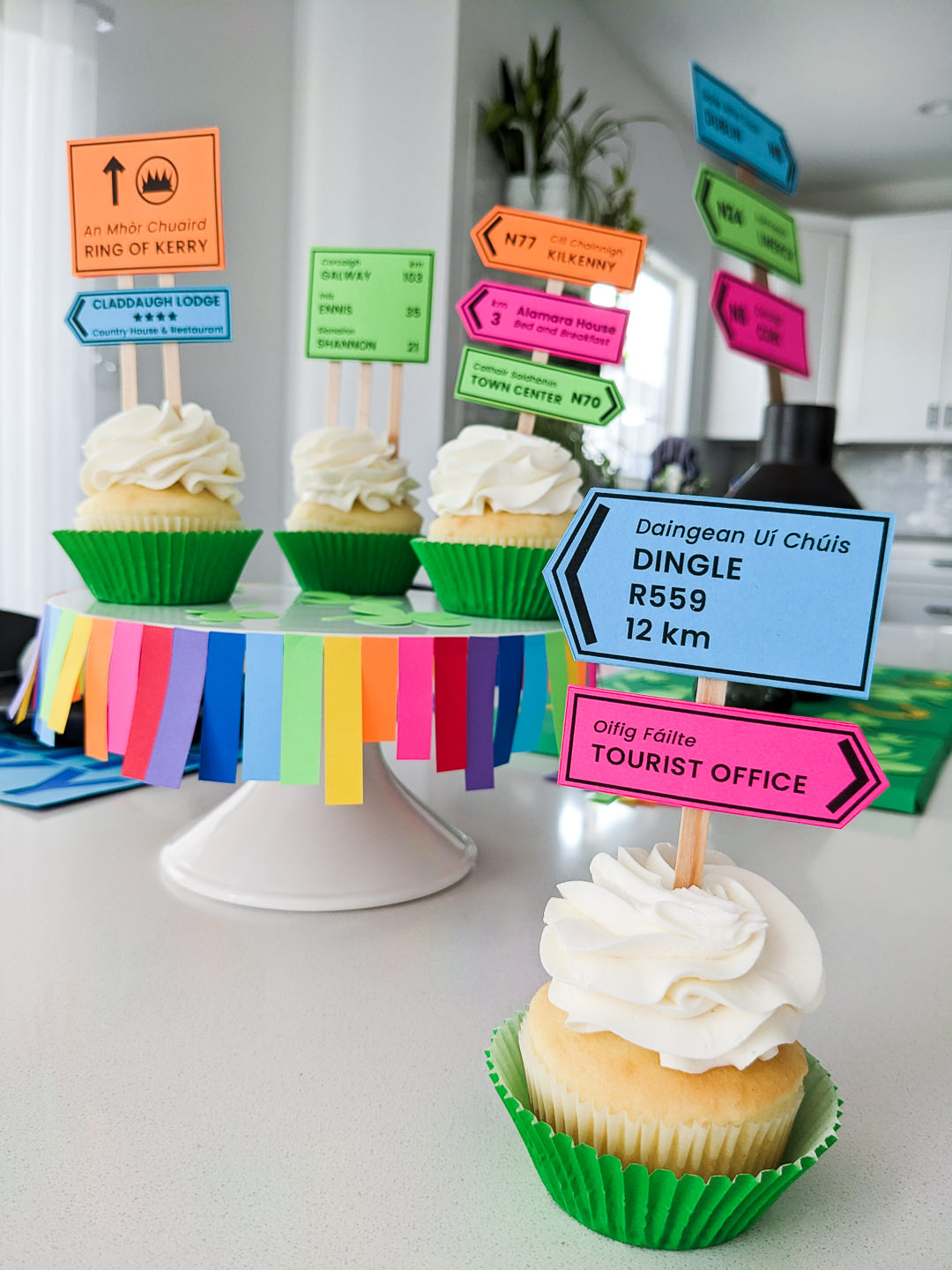 St. Patrick's Day cupcakes with Irish road signs cupcake toppers with green cupcake liners sitting on a DIY rainbow cake stand
