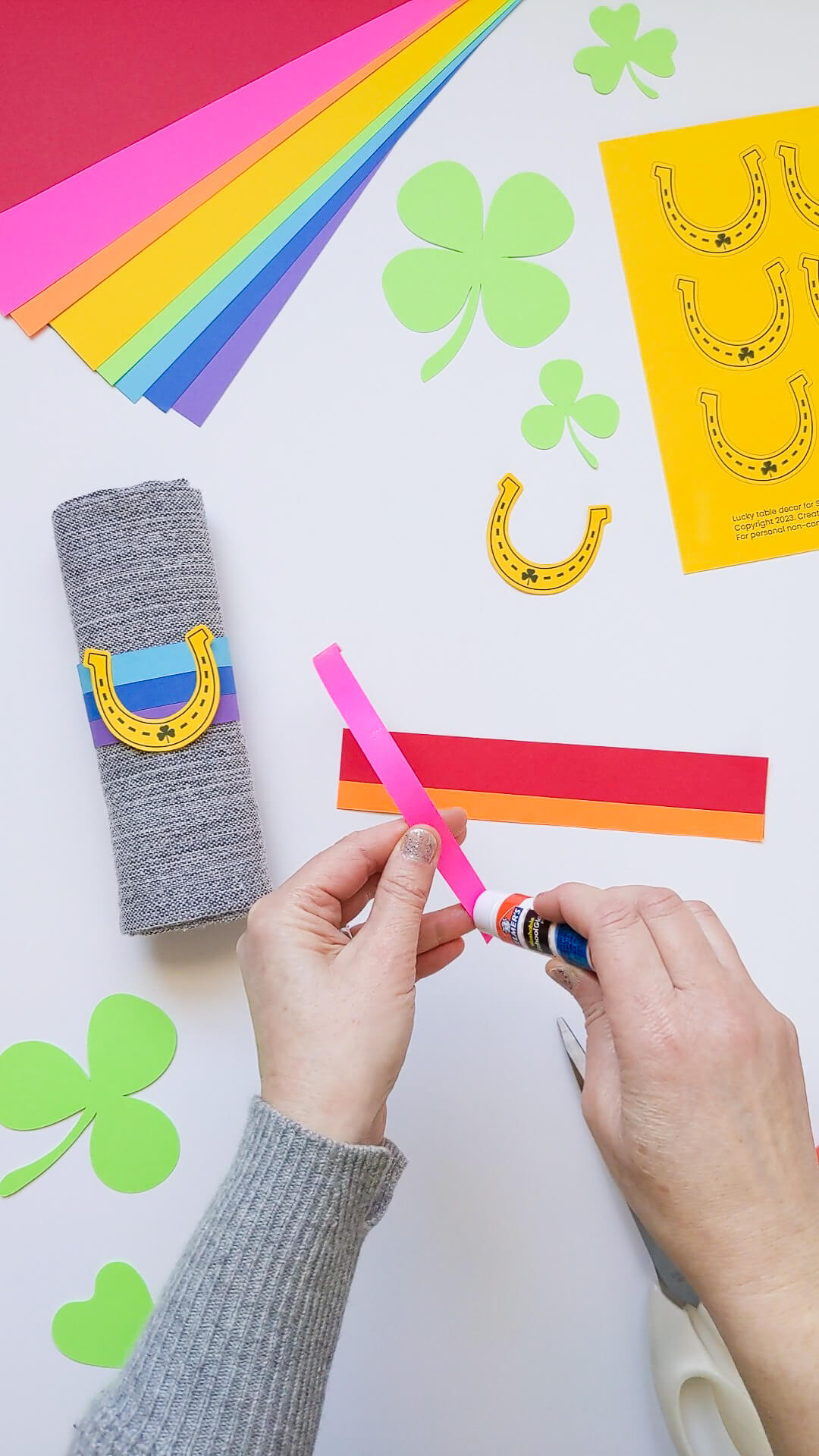 Gluing DIY rainbow napkin rings for the St. Patrick's Day dinner table