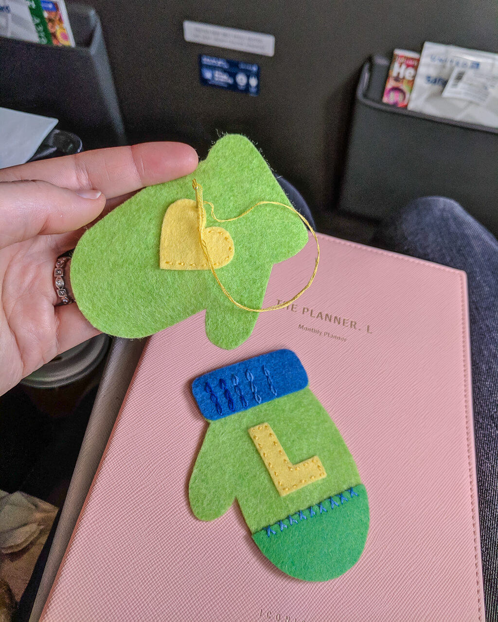 Embroidering felt mini mitten ornaments while on a plane